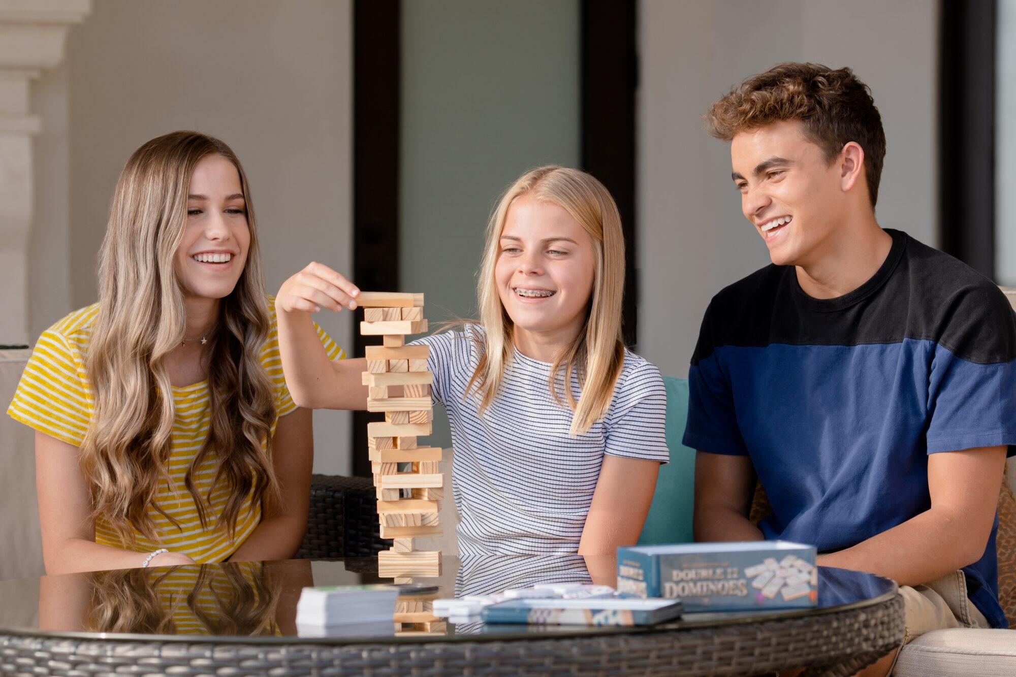 Three smiling teens playing Jenga