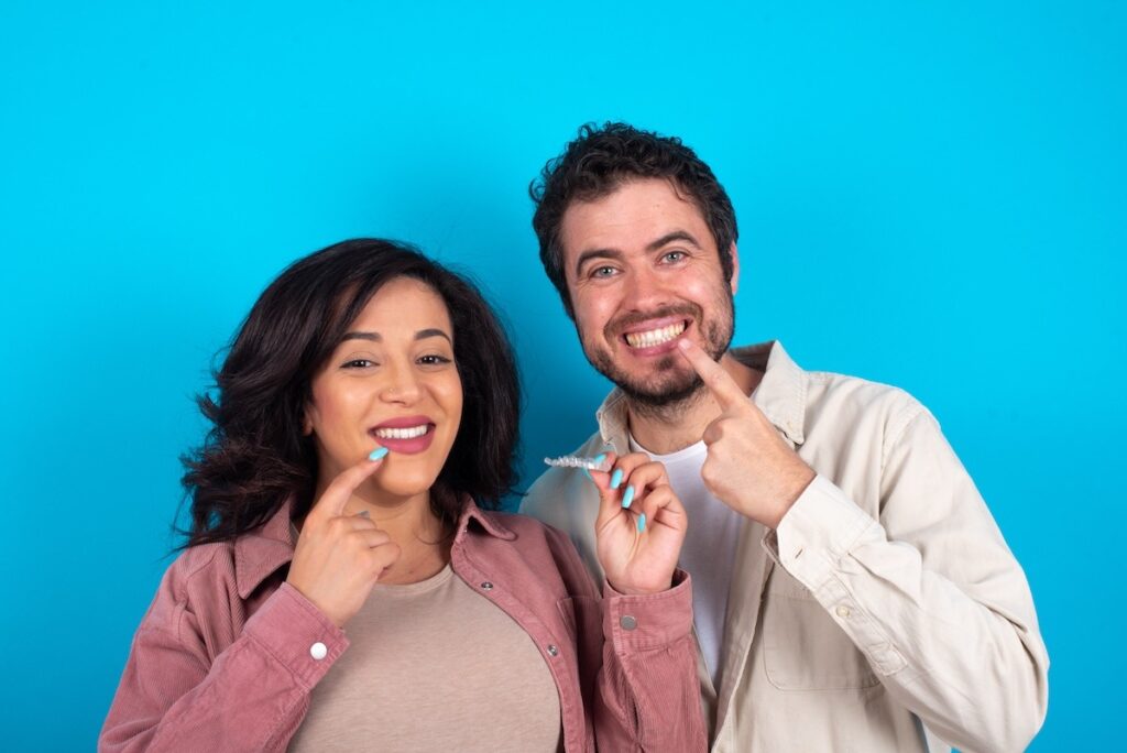 A man and a woman smiling after finish Clear aligners treatment.