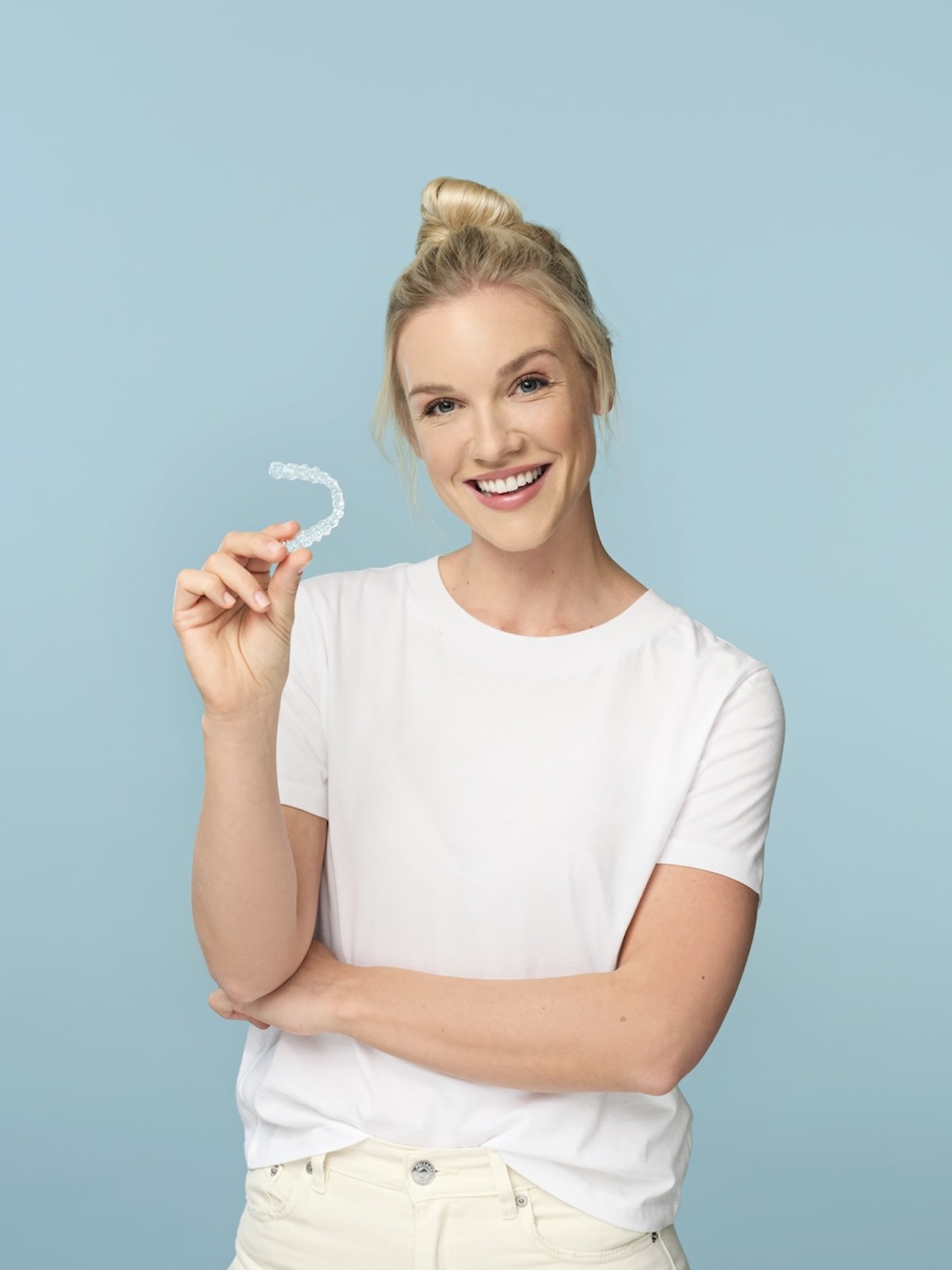 Smiling woman holding clear aligner.