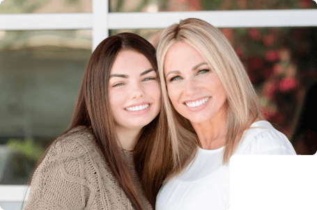 2 adult women smiling who now have nice straight teeth after finishing orthodontic care.