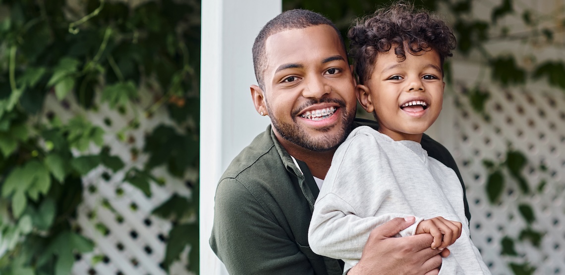 Man with metal braces embracing son outside