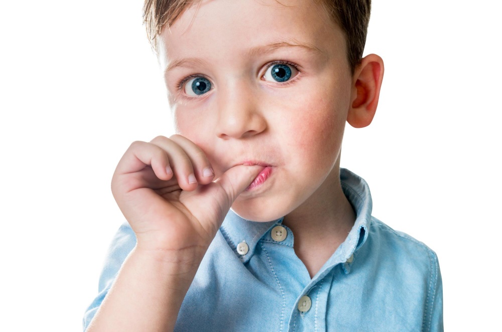 Young boy wearing a blue button up shirt while sucking his thumb.