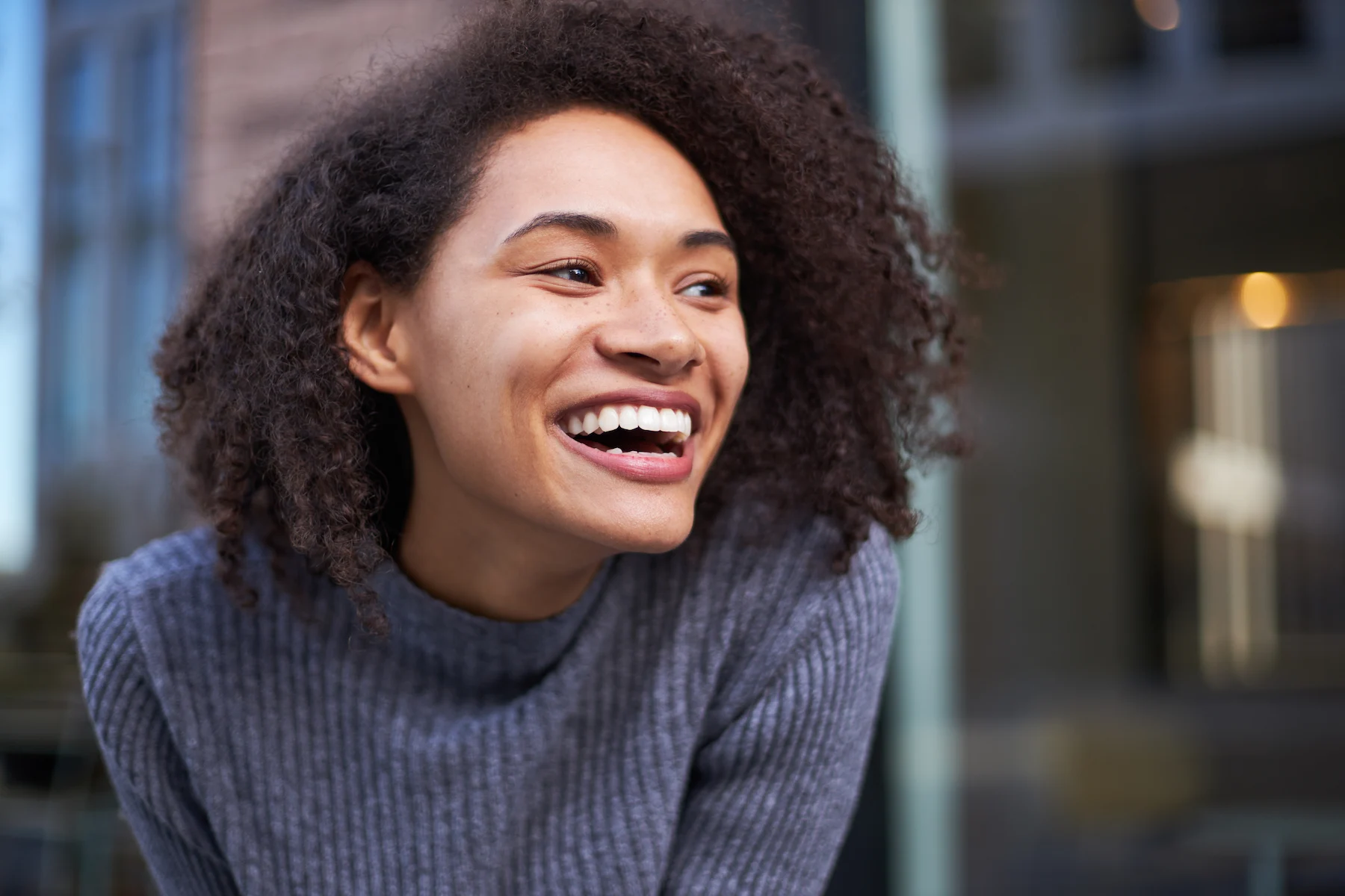 Smiling woman in a gray sweater.