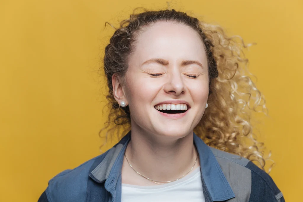 Smiling woman in front of a yellow backdrop.