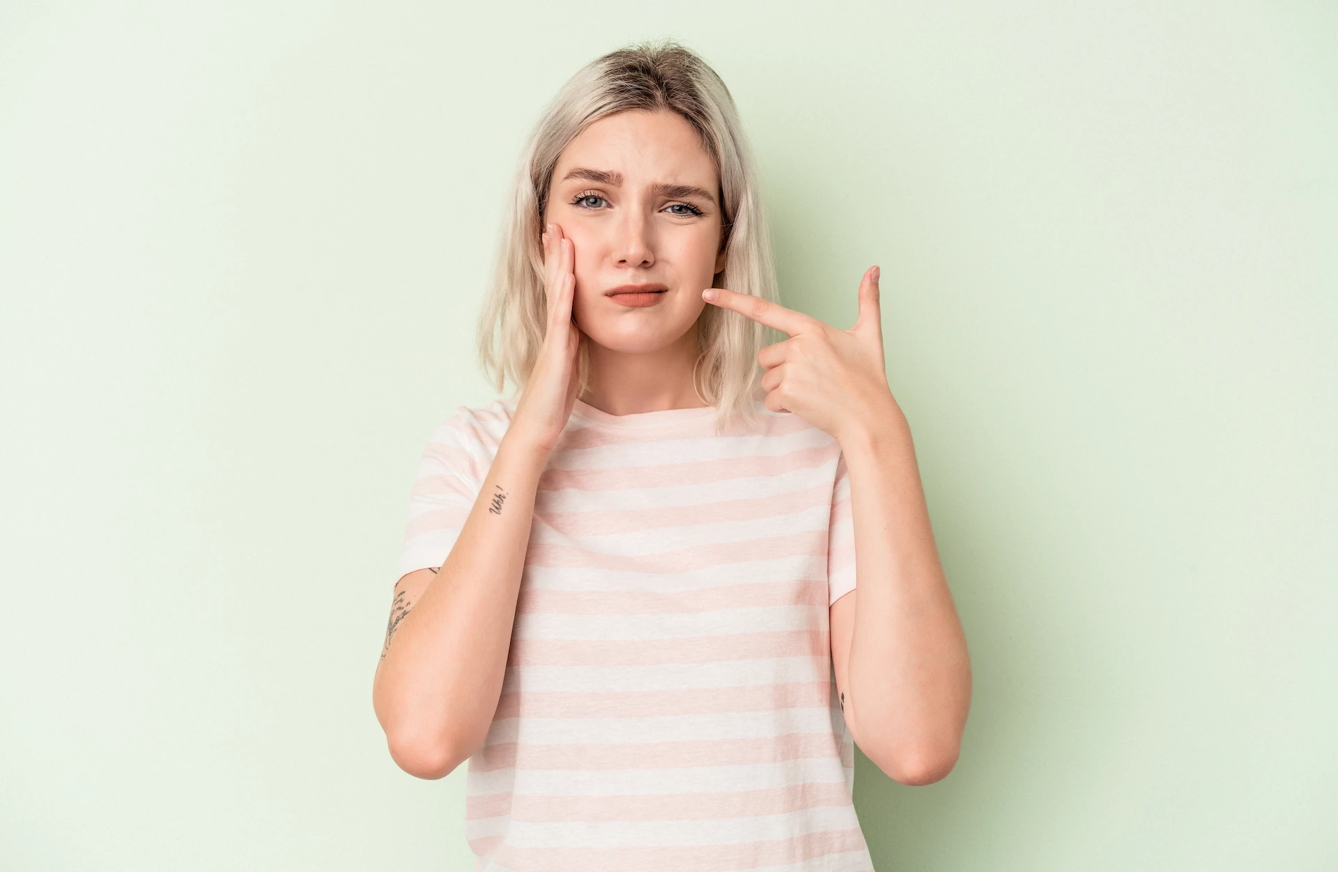 Girl with braces pointing to her cheek because they are cutting the side of her mouth.