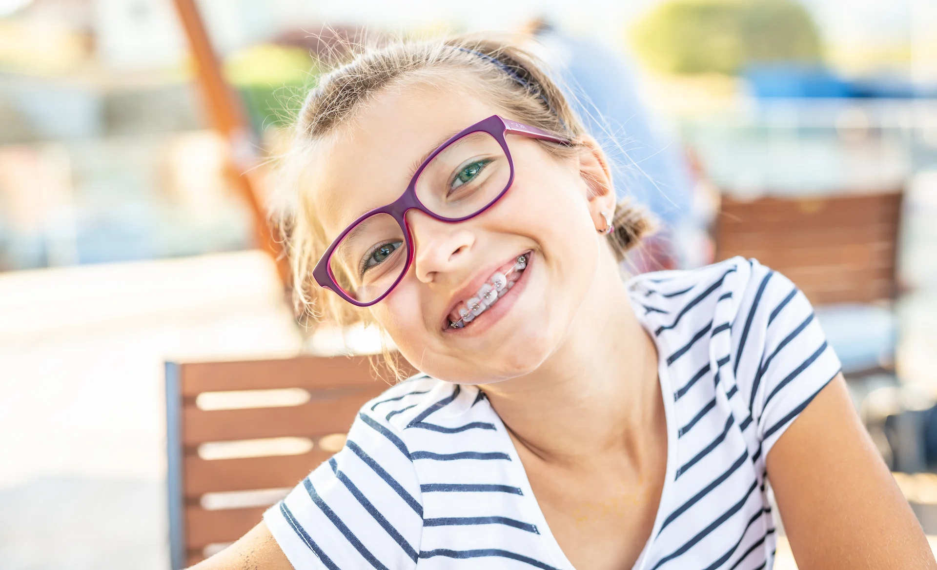 Smiling girl in pink glasses wearing braces.