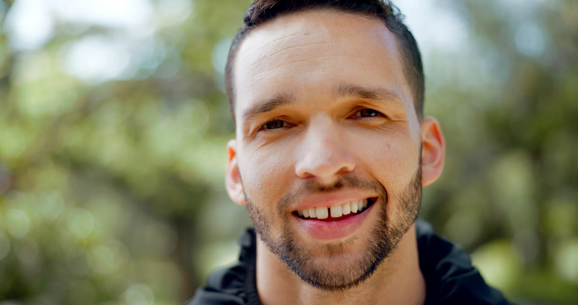 Smiling man with a gap in his front teeth.
